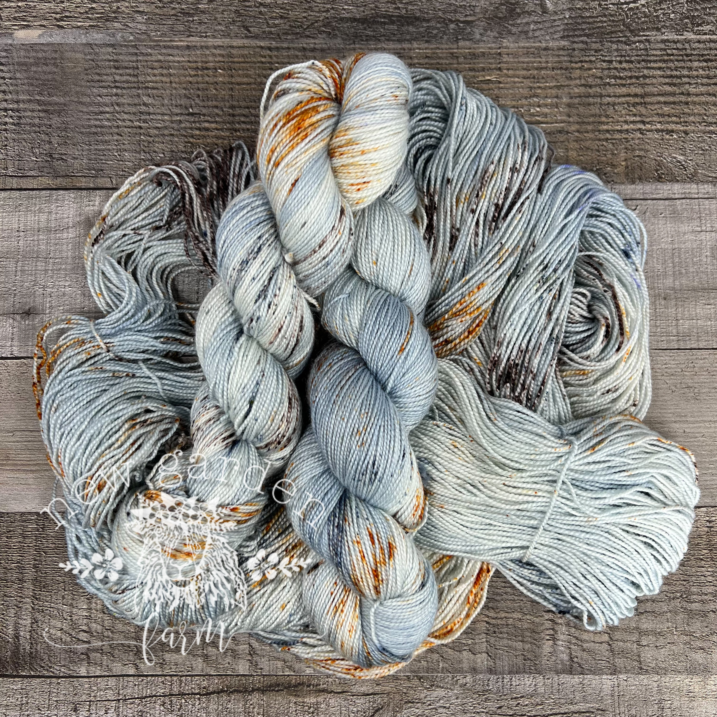 wool silk hand dyed yarn with pale blue grey background and speckled with brown rust and grey blue