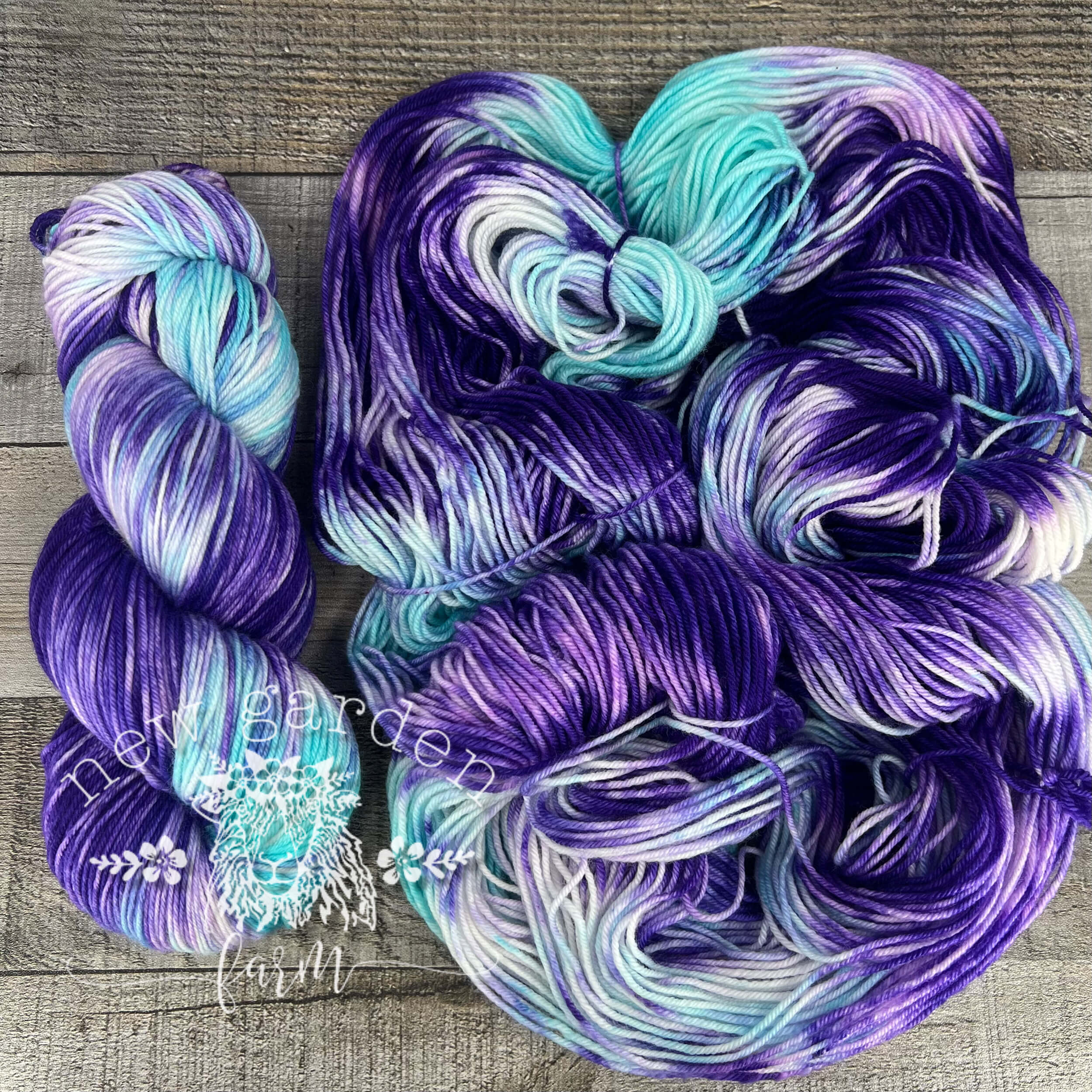 Iris hand dyed yarn, pale aqua and purple laying on a barn wood background